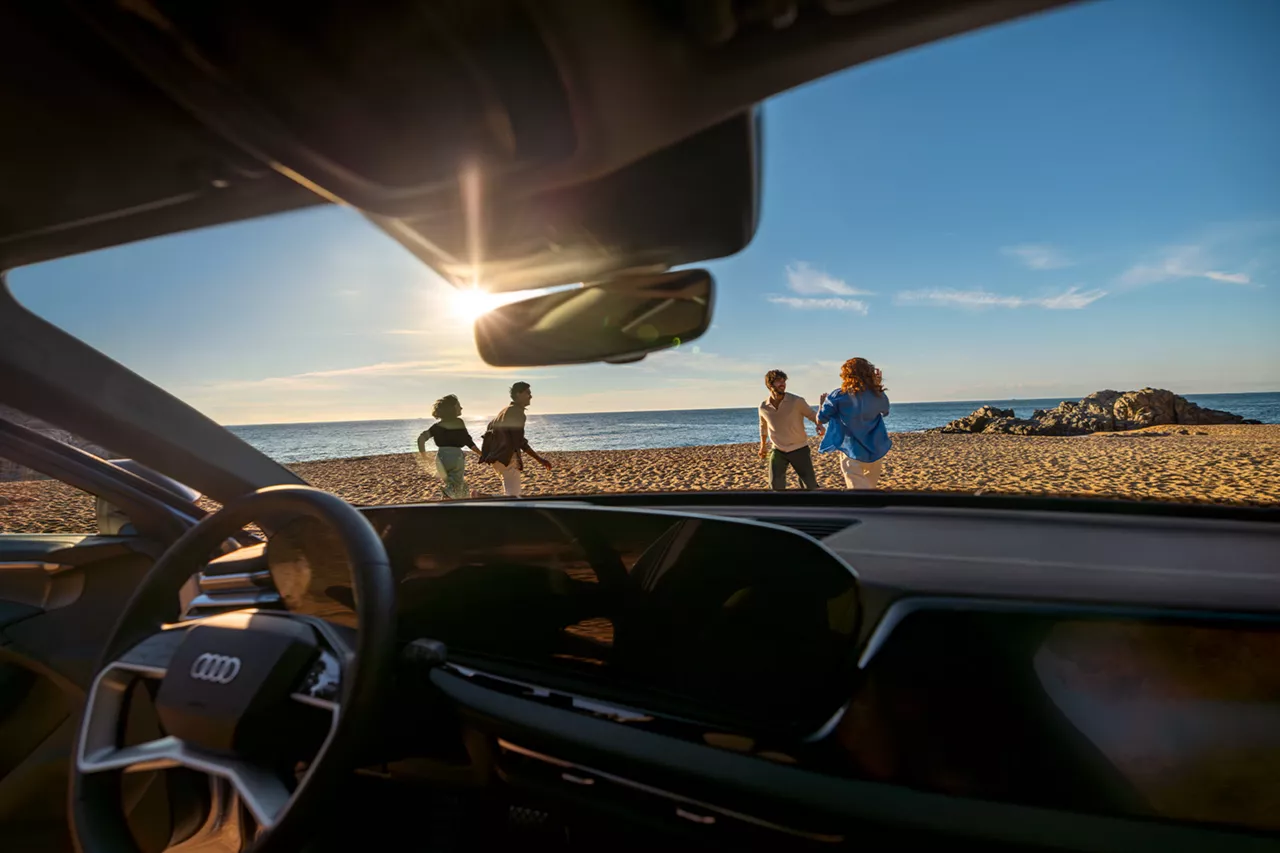 Fahrerperspektive, vier Personen sind hinter der Windschutzscheibe am Strand zu sehen