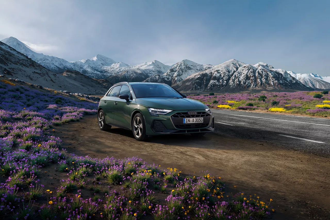 Ein dunklegrünes Audi Modell steht in in einer Berglandschaft.