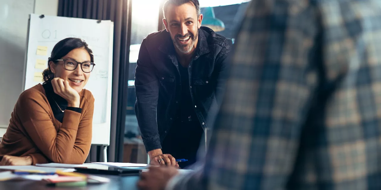 3 pessoas conversando sorrindo em um ambiente de trabalho