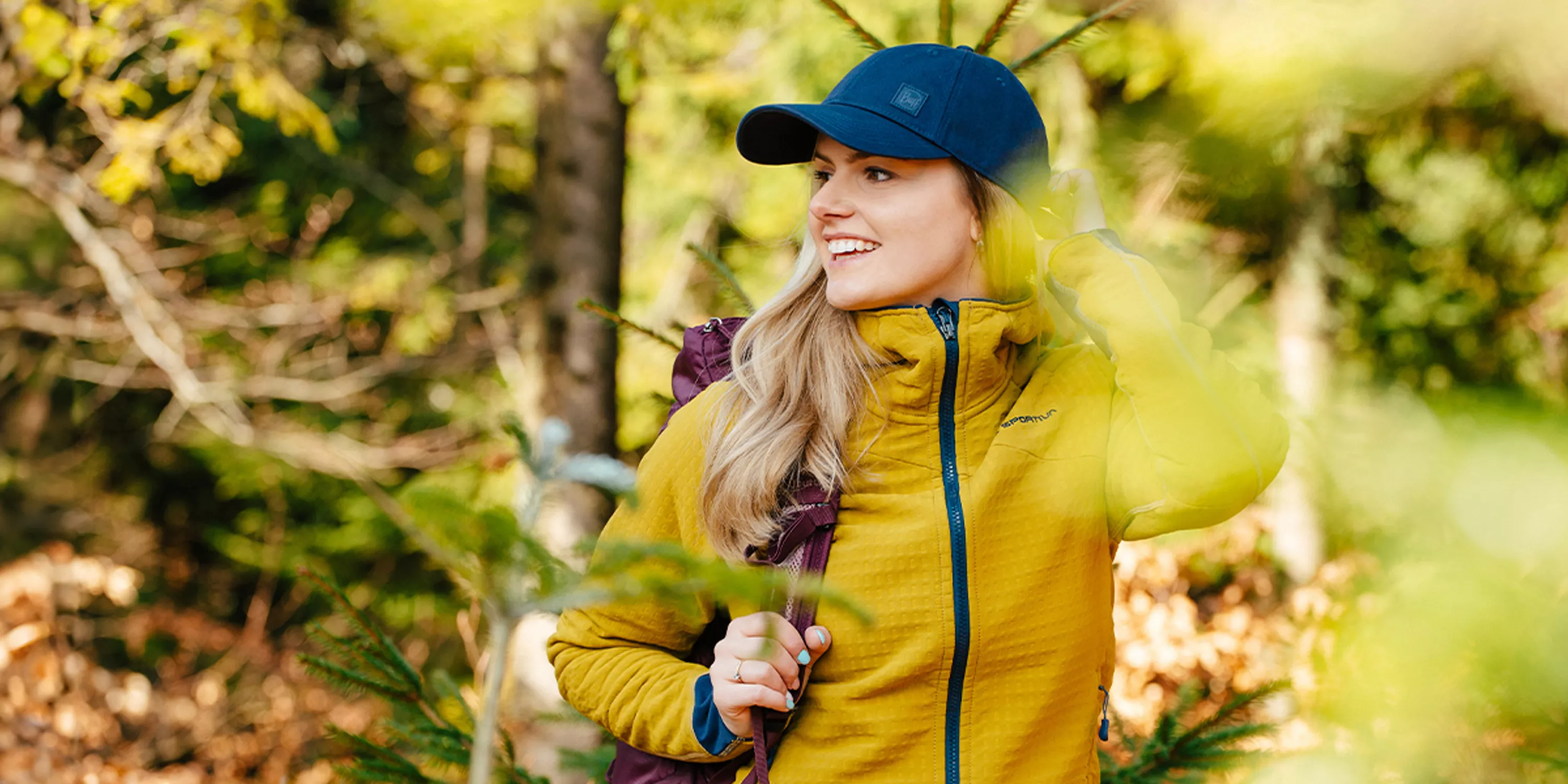 Uśmiechnięta kobieta na szlaku górskim spogląda w dal.