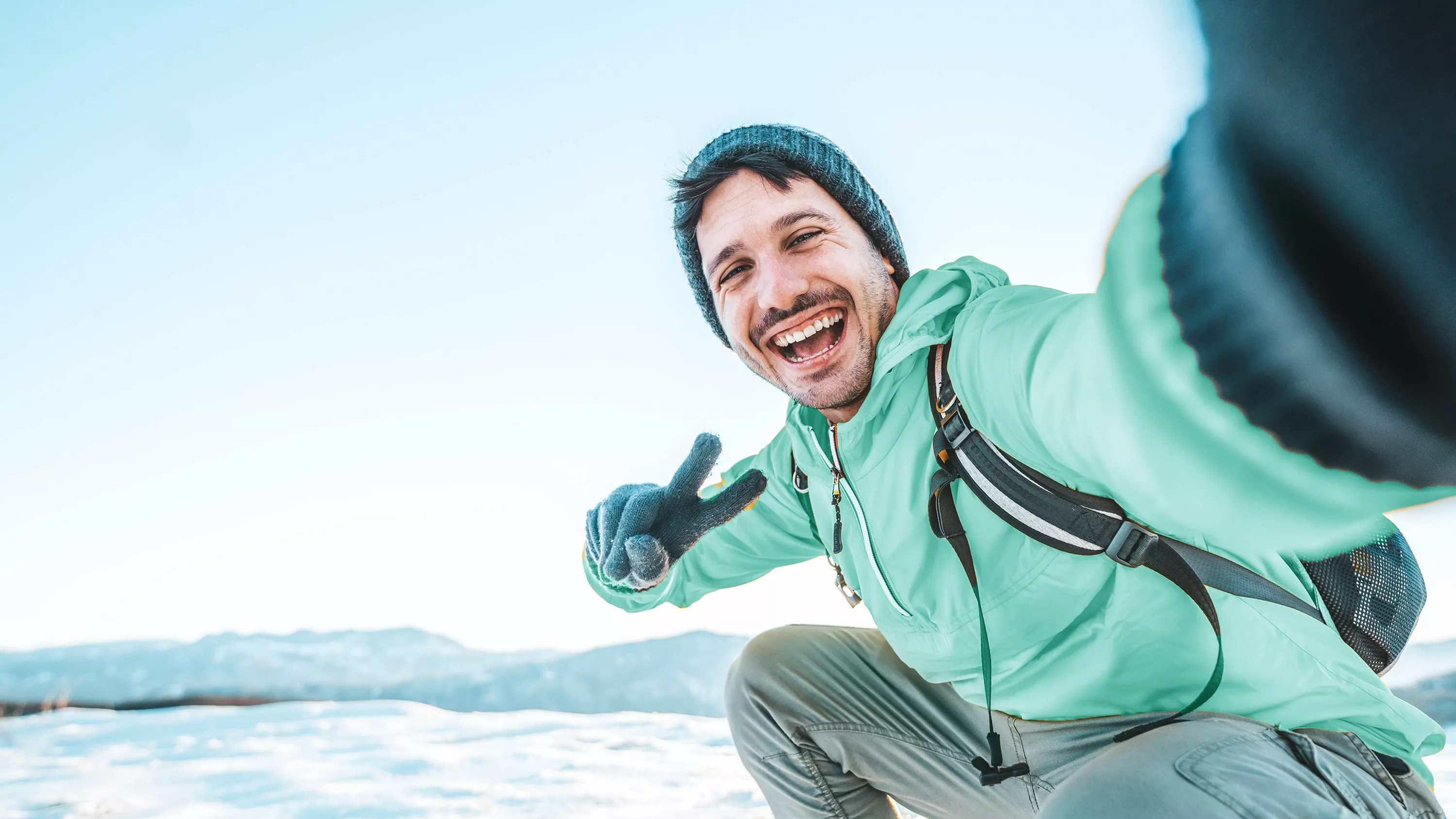 Uśmiechnięty mężczyzna wykonuje selfie w zimowej scenerii.