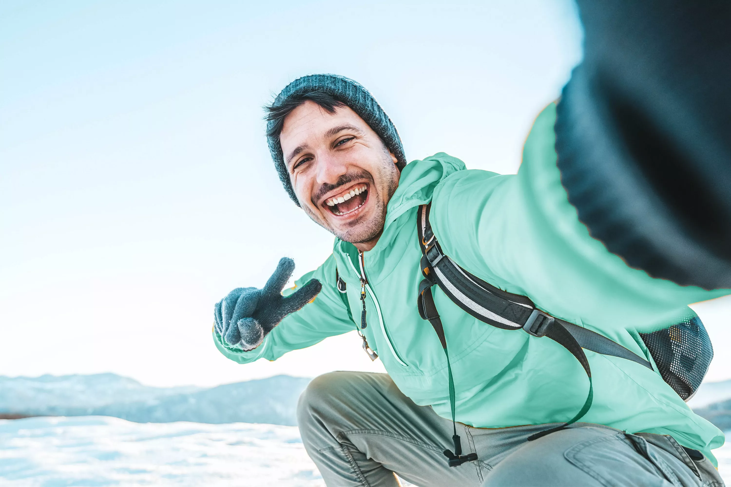 Uśmiechnięty mężczyzna wykonuje selfie w zimowej scenerii.