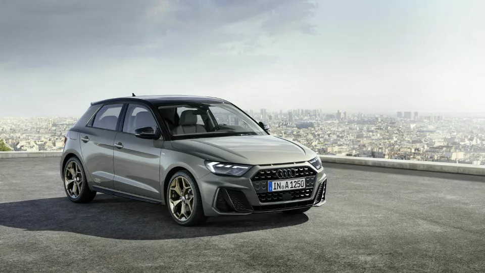 Vista lateral de un coche de Renting Audi A1 Sportback Advanced, diésel, color blanco, aparcado delante de un edificio 