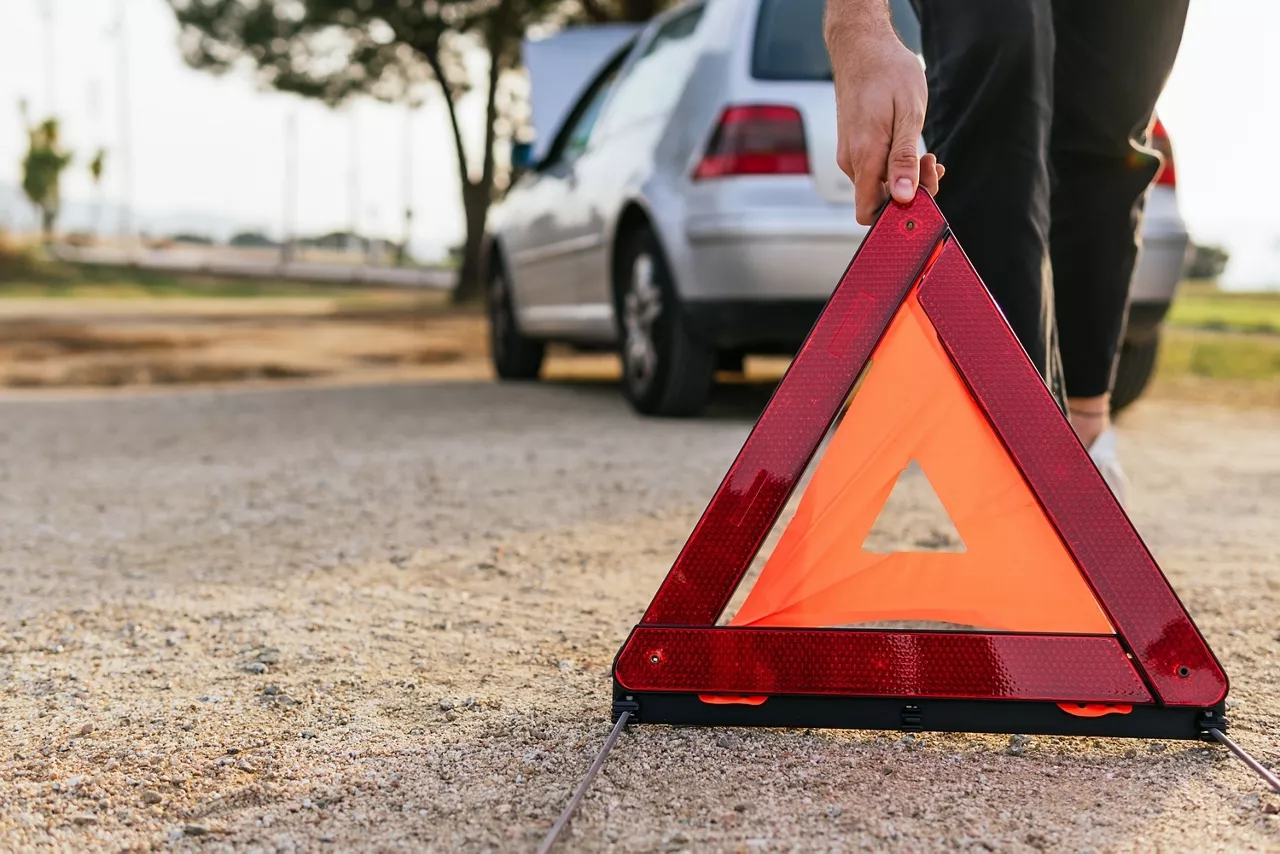 Warndreieck wird aufgestellt. Im Hintergrund ist ein Auto zu sehen.