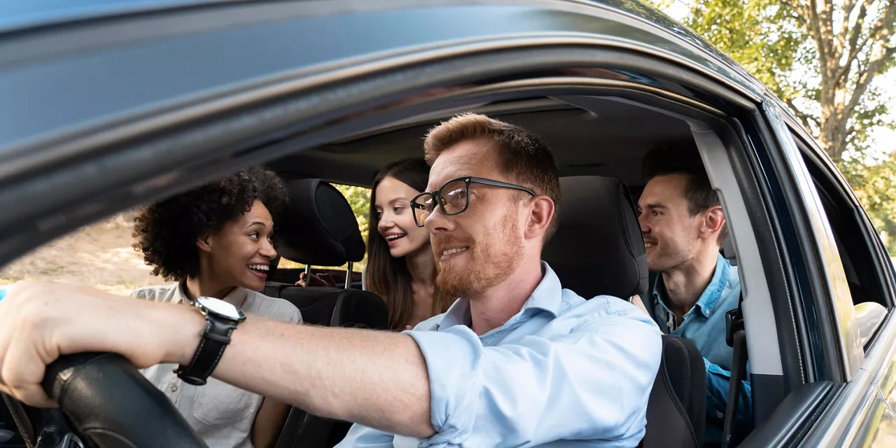 Seguro Volkswagen: quatro amigos conversando dentro de um carro enquanto um deles dirige o automóvel. 