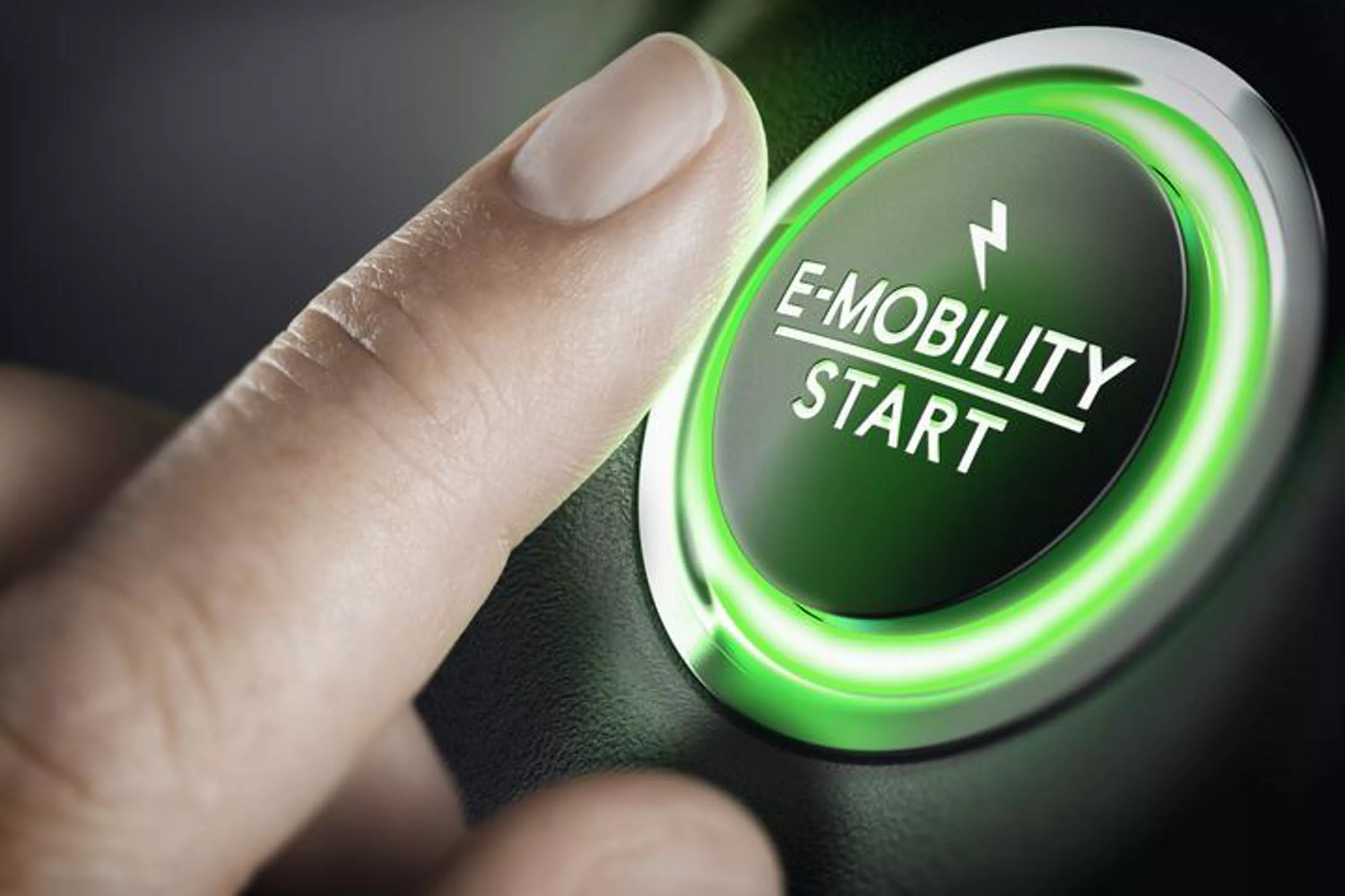 Nahaufnahme einer Hand: Finger drückt Startknopf für E-Mobilität.