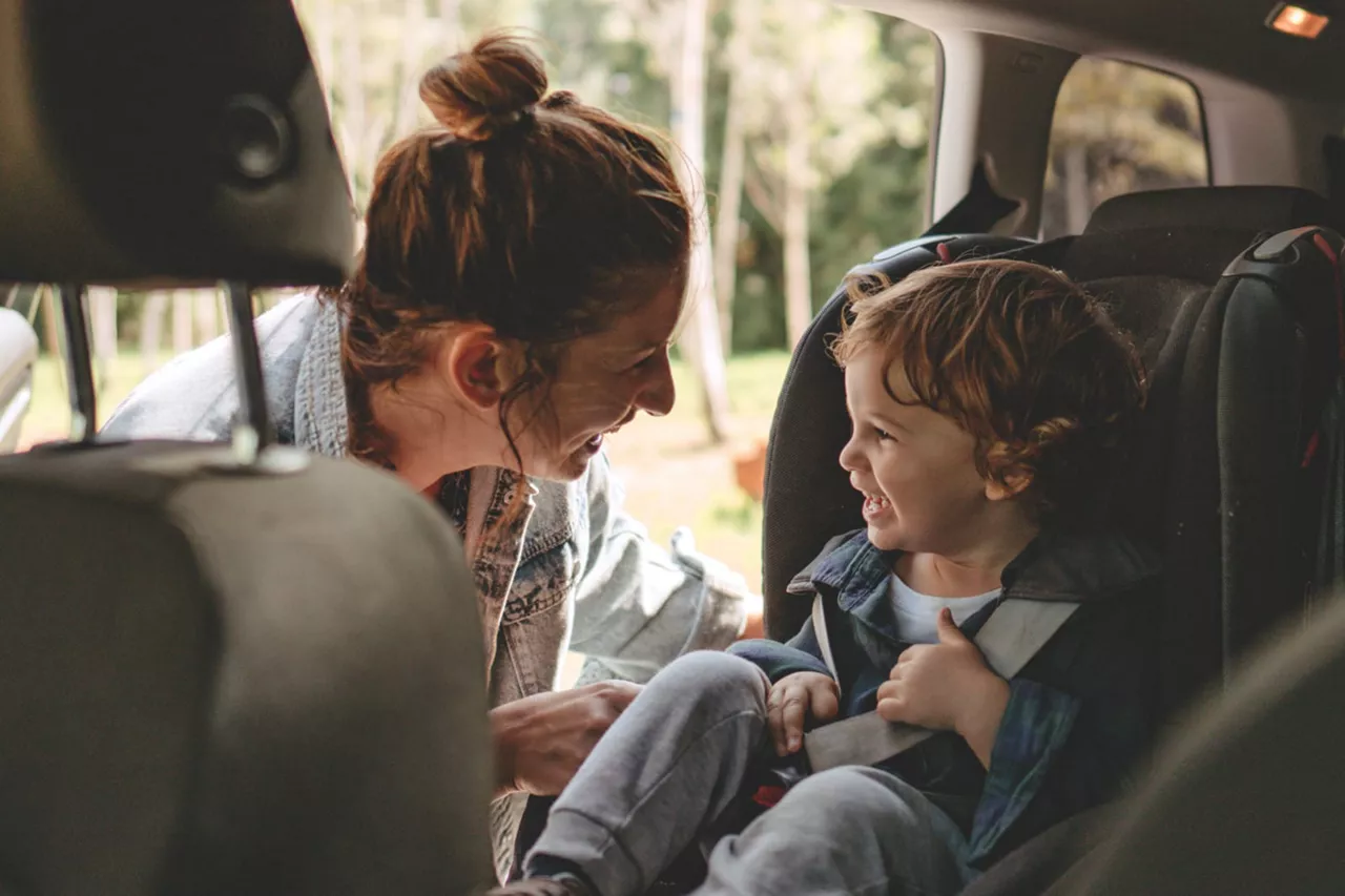 Una madre acomodando a un niño en una silla en un coche de financiación