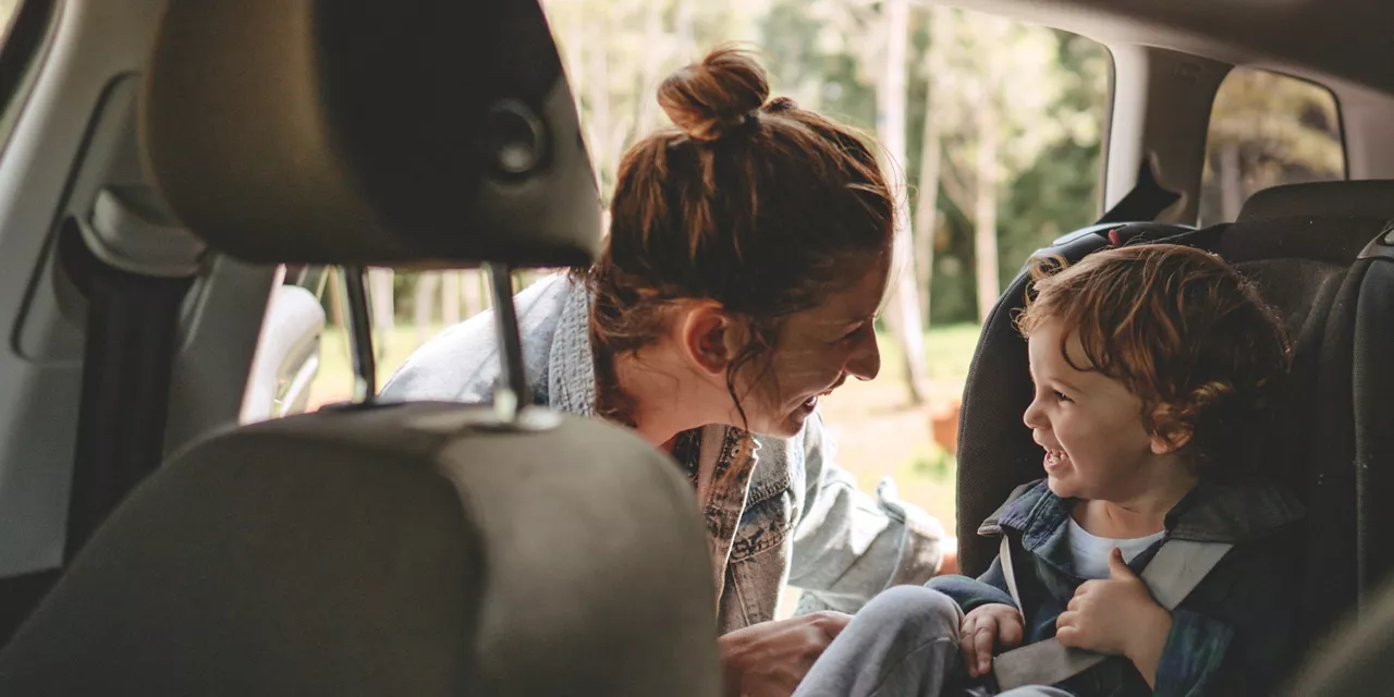 Una mujer acomoda a un niño en una silla infantil en un coche de financiación del Grupo Volkswagen.