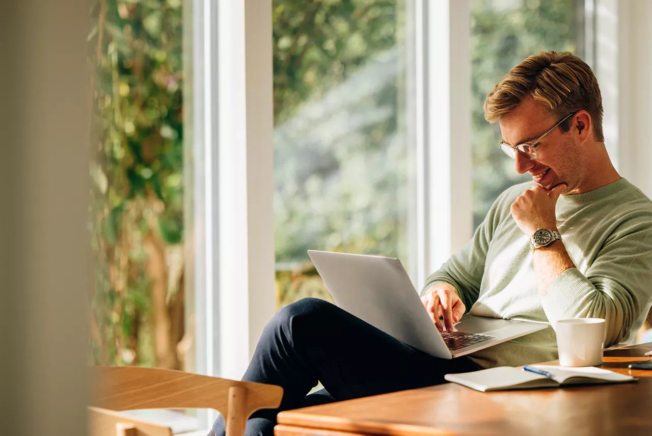 Un hombre sentado en una silla consultando su ordenador