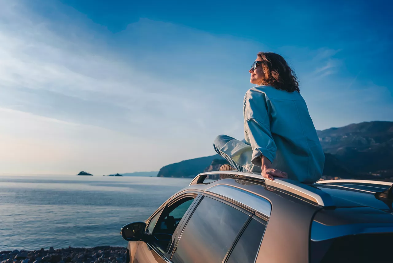Una mujer sentada en el techo de un coche VW