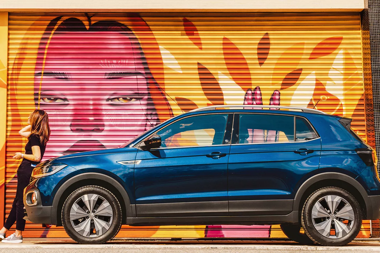 Seguro de Proteção Financeira Volkswagen: mulher sentada na frente de um T-Cross azul.