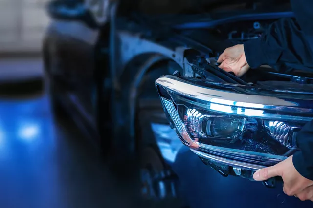 Una mano de una persona arreglando luz delantera del coche