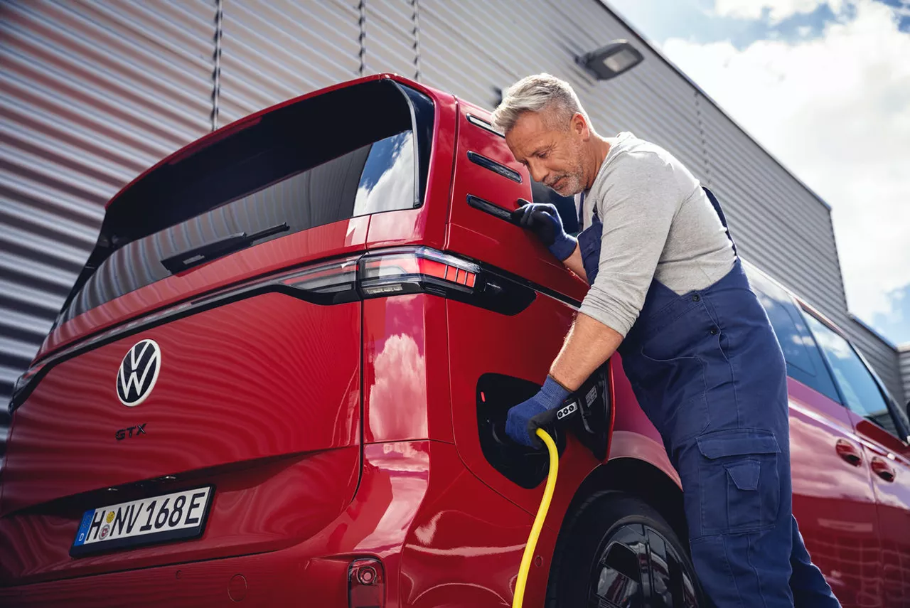 Un chica espera junto a su coche electrico financiado por Volkswagen Financial Services hasta que este cargado.