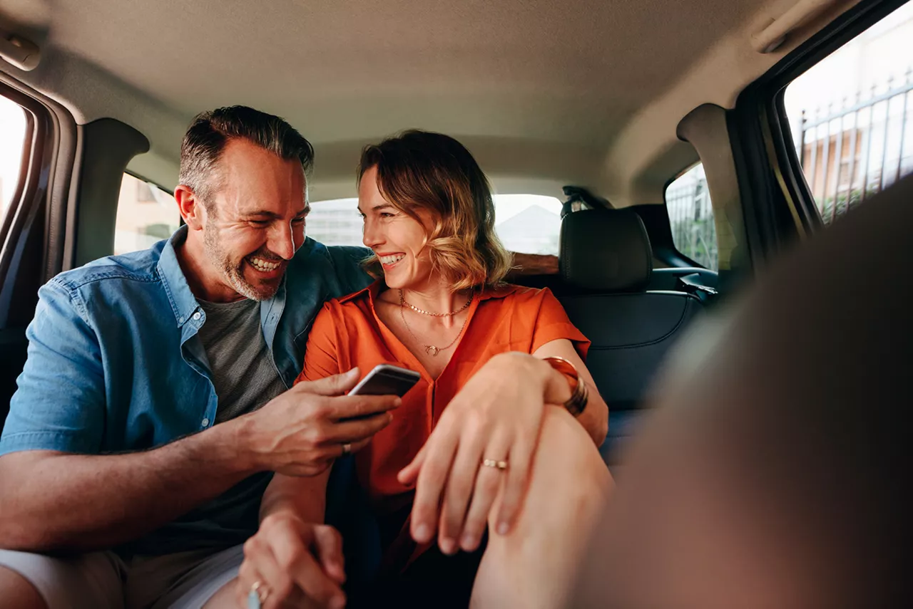 Pareja joven conversa sentada dentro de un coche del grupo Volkswagen
