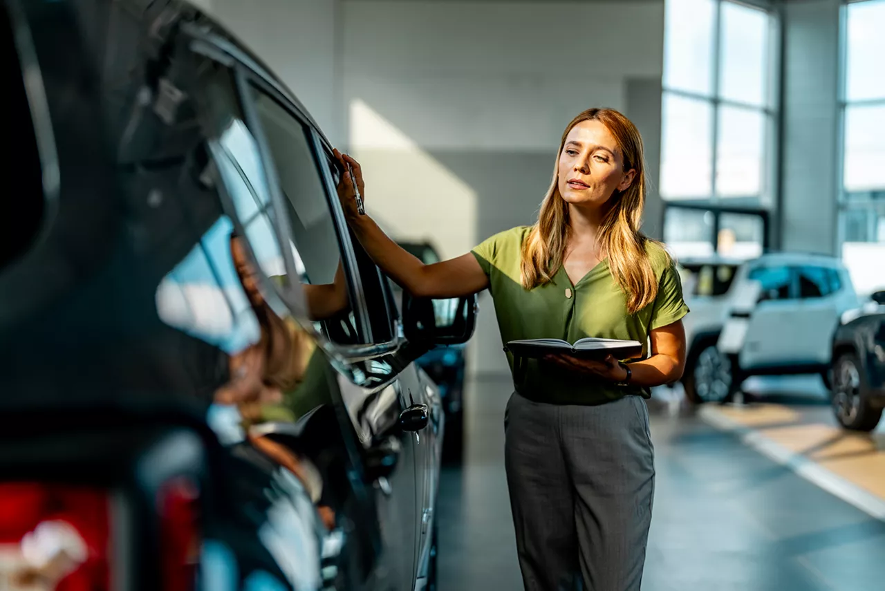 Una mujer apoyada en un coche del Grupo Volkswagen