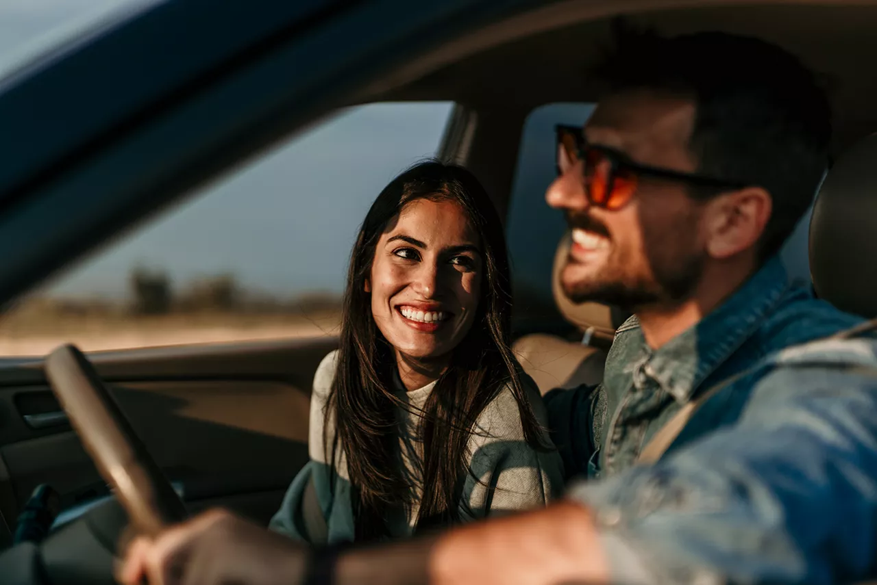 Una pareja sonriendo dentro de un coche de Renting del Grupo Volkswagen