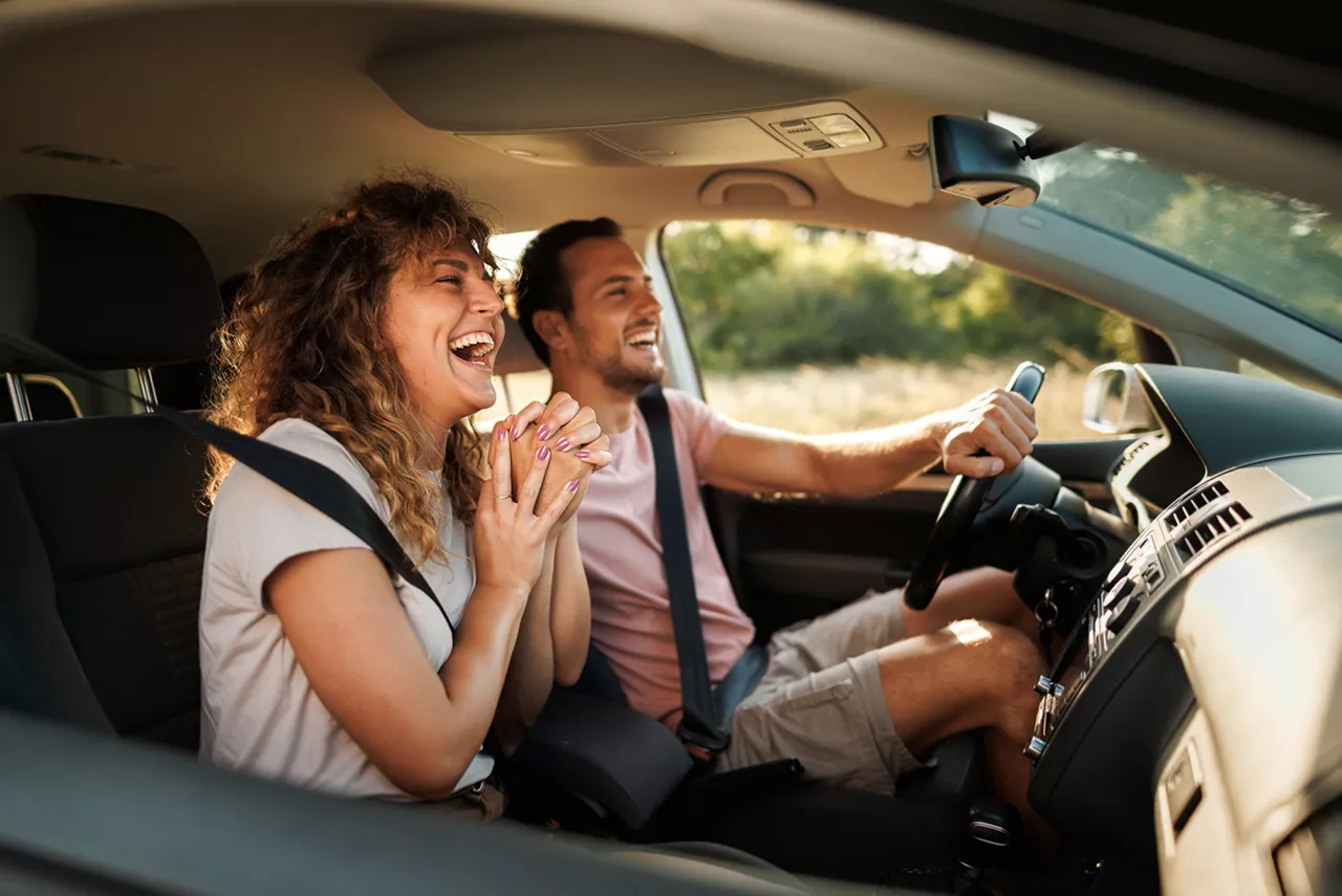 Una pareja sonrieno dentro de un coche del grupo Volkswagen