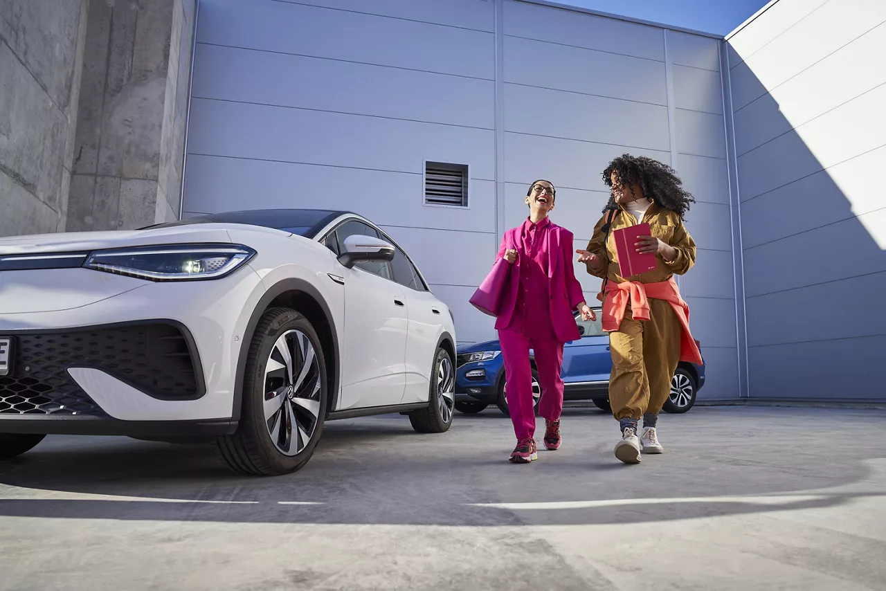 Dos chicas sonriendo junto a un coche nuevo ofertas del Grupo Volkswagen