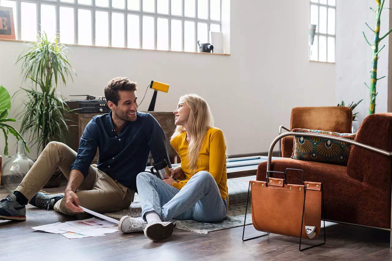 Una pareja hablando sentada en el suelo del salón de casa