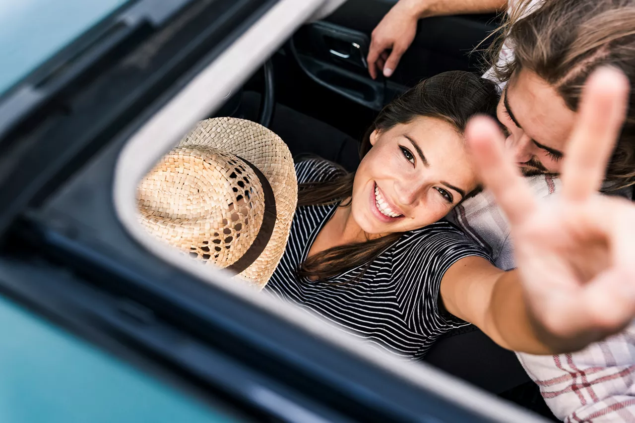 Pareja en el interior de un coche vista a través del techo solar abieto