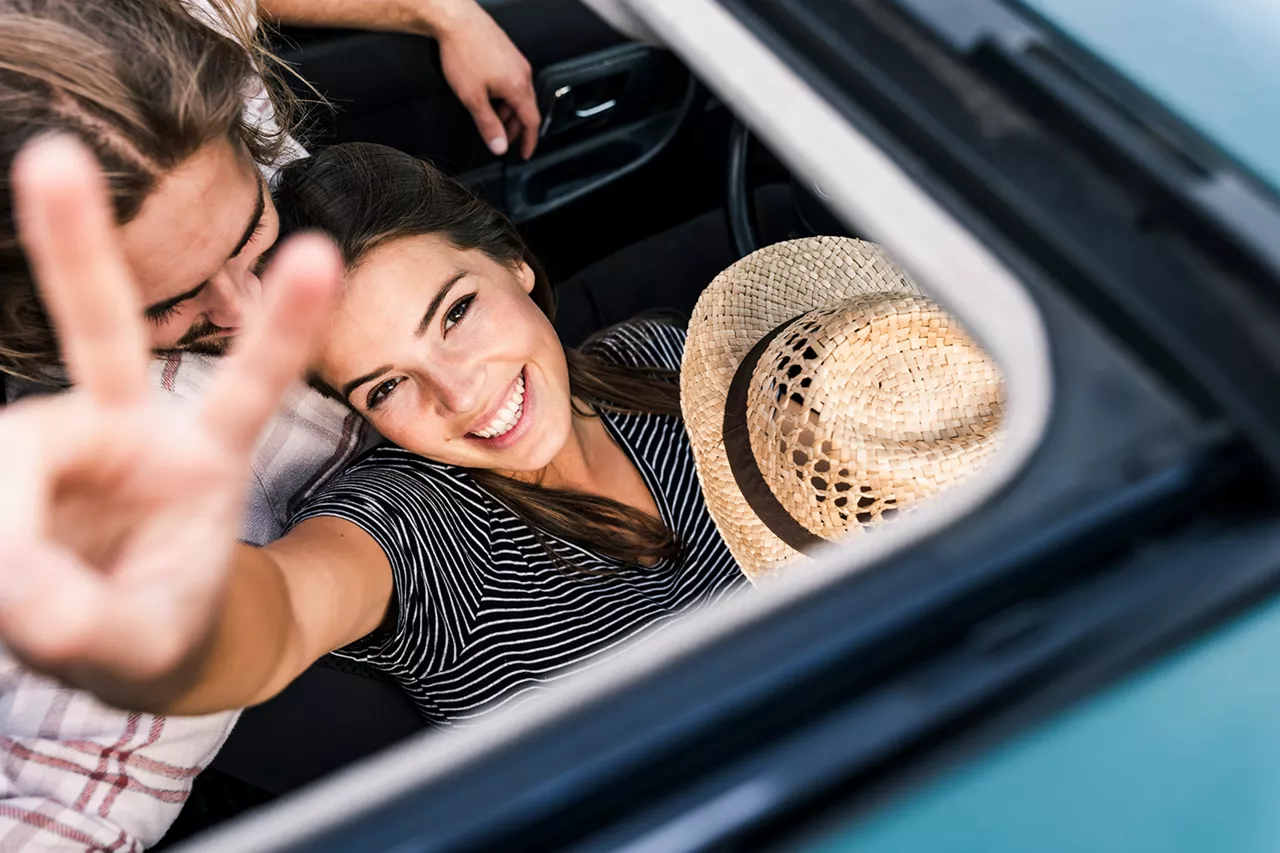 Pareja sonriendo vista a través del techo solar de un coche del Grupo Volkswagen