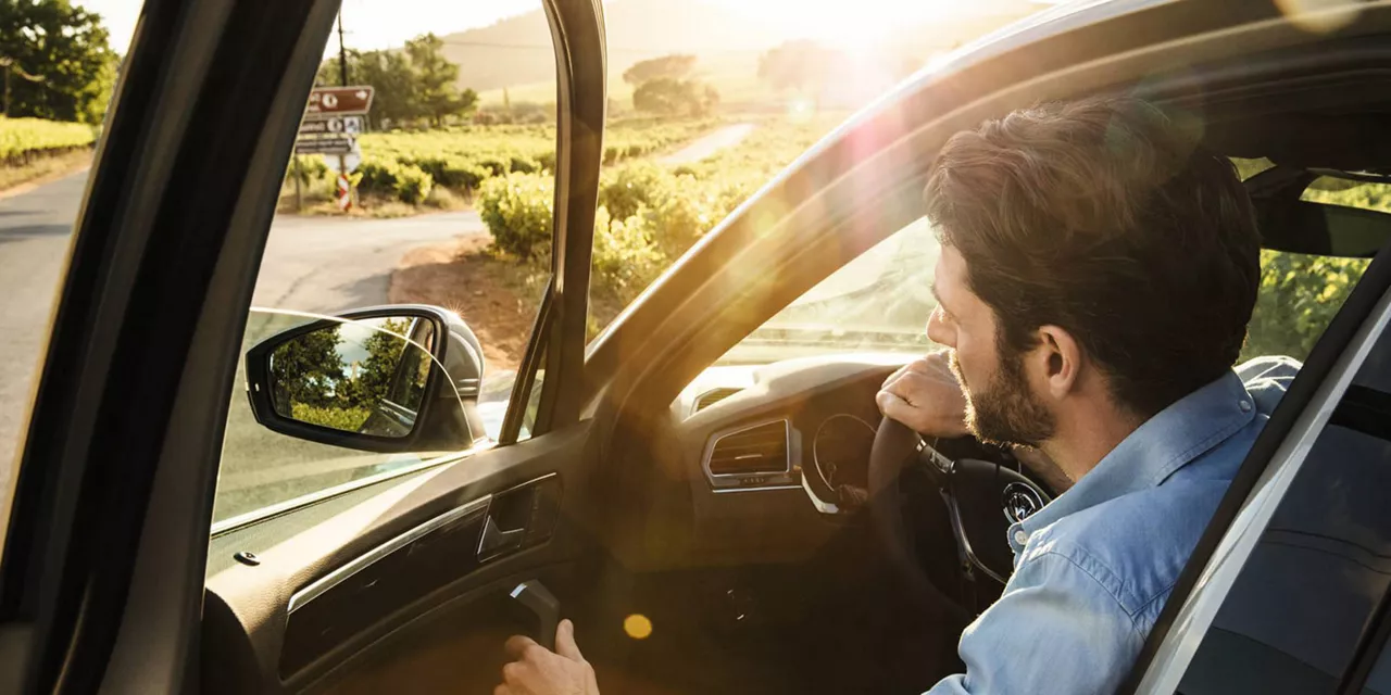 Hombre joven subiendo a un coche de Renting detenido en una carretera