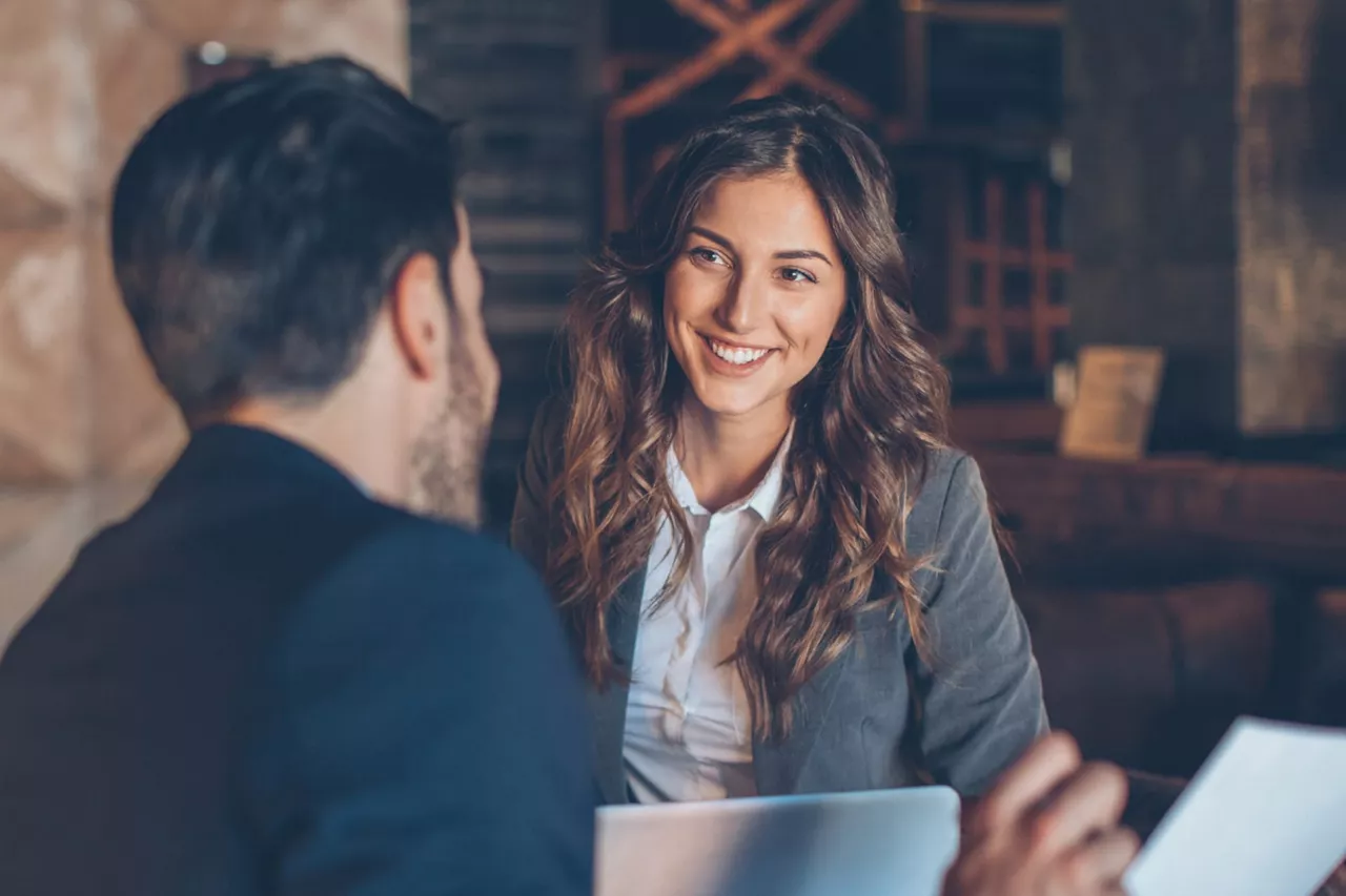 Una chica sonriendo hablando con un hombre de espaldas