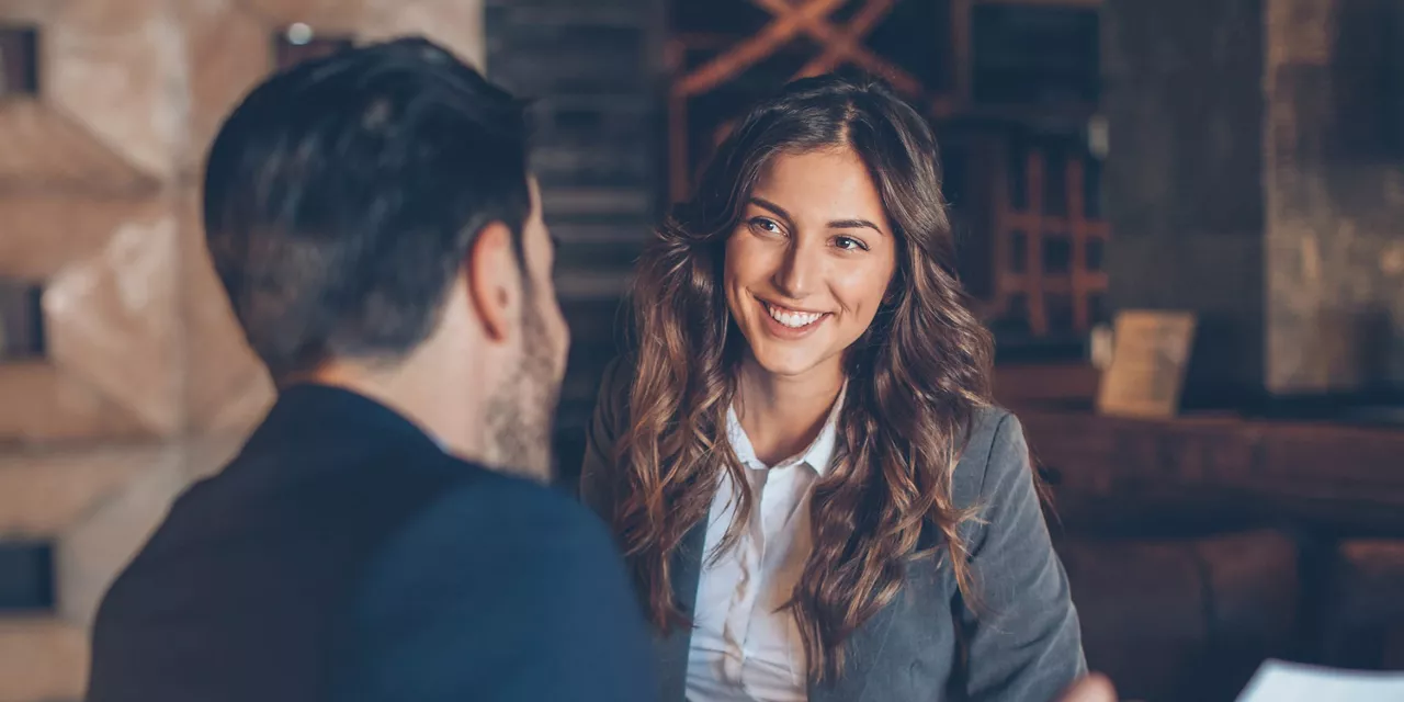 Una chica sonriendo hablando con un hombre de espaldas