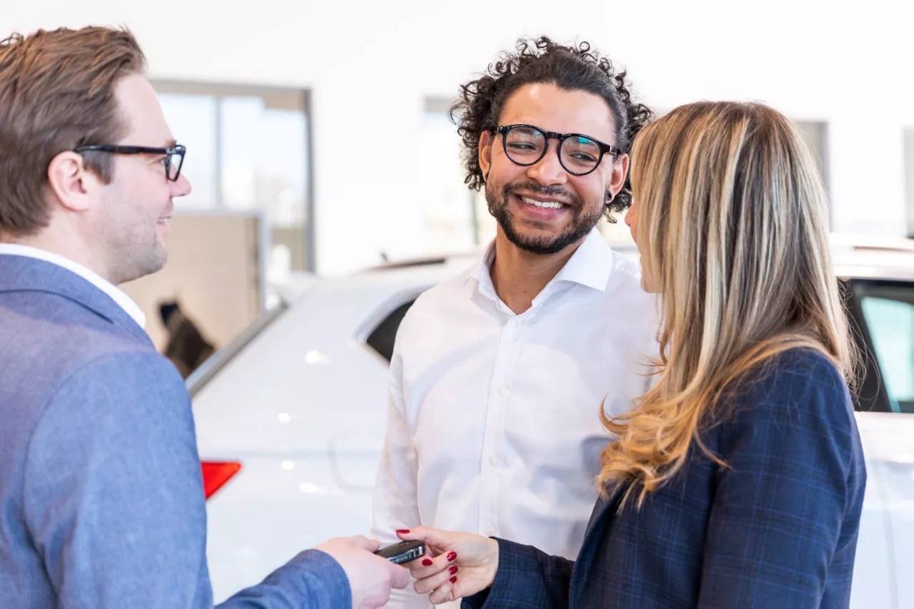 Consulente Volkswagen che dialoga con dei clienti all'interno di una concessionaria.