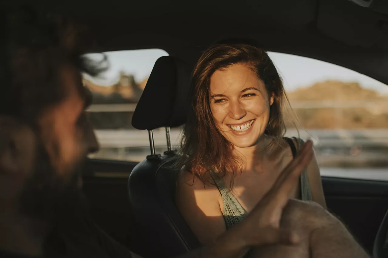 Una chica sonriendo sentada al volante de un coche de Renting del Grupo Volkswagen