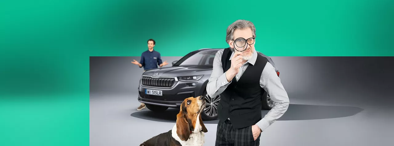 Starszy mężczyzna z lupą przyłożoną do oka. Za nim szara Skoda Kodiaq i młody sprzedawca, który zaskoczony rozkłada ręce. Mężczyznę obserwuje pies.