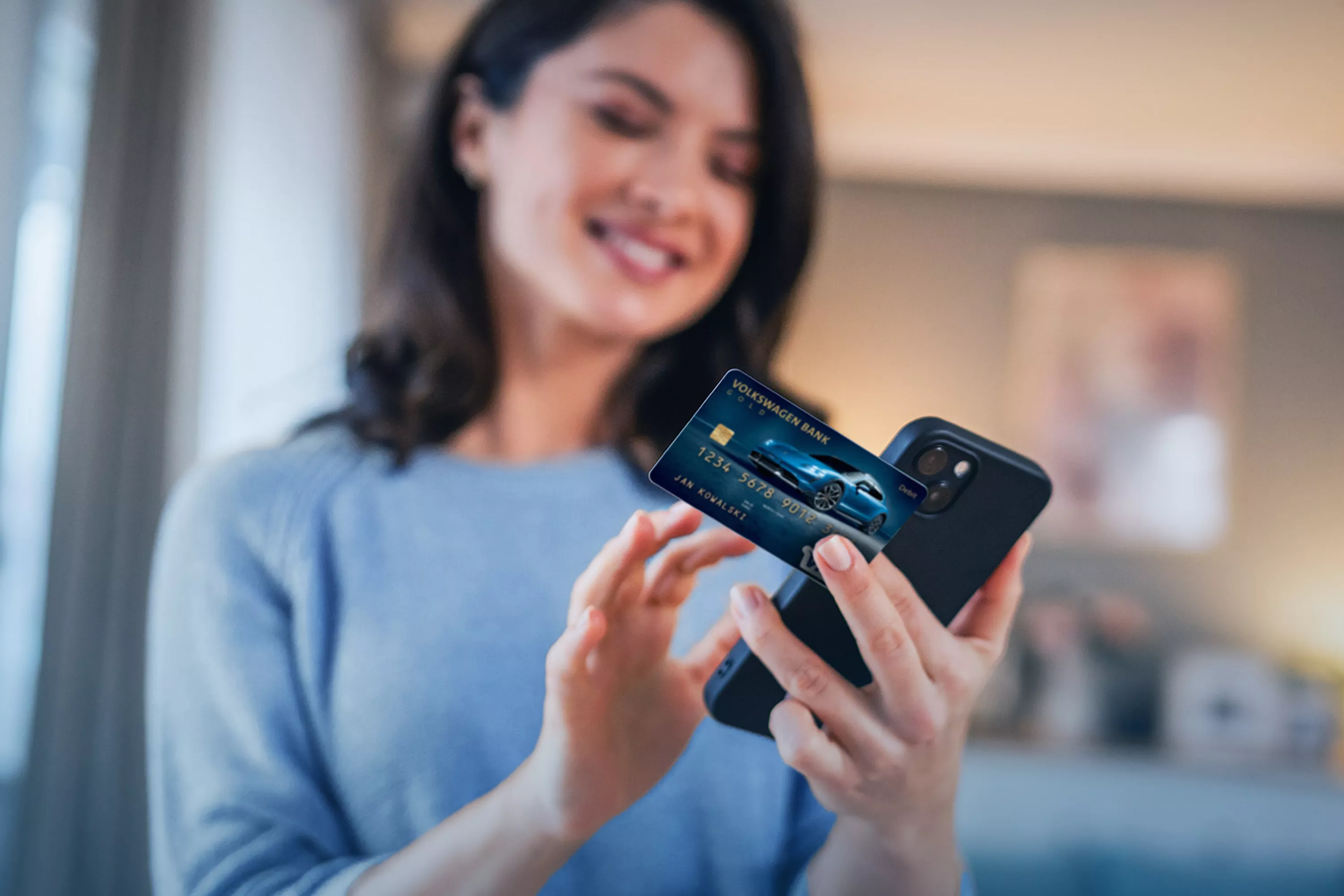 Kobieta wpisująca dane z karty bankowej do telefonu komórkowego.