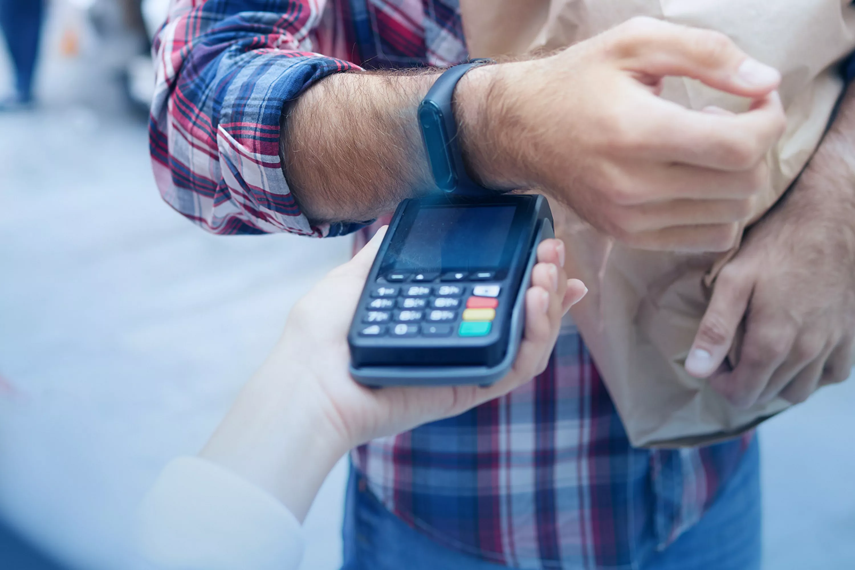 Mężczyzna płacący za zakupy zbliżeniowo opaską Xiaomi.