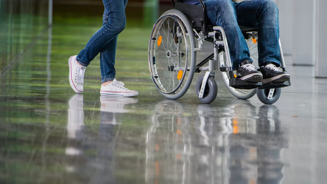 Eine Person schiebt eine andere im Rollstuhl sitzende Person