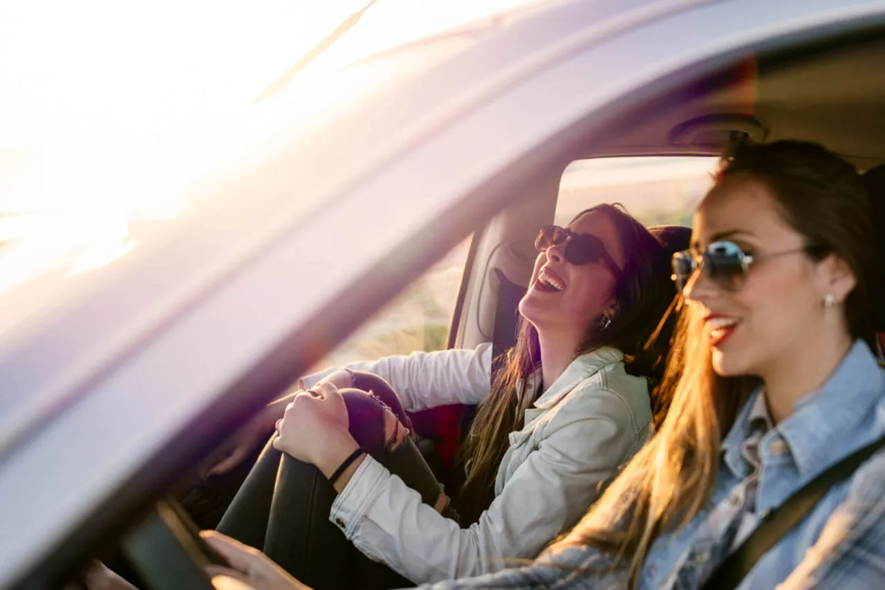 Dos chicas sonriendo dentro de un coche de Renting del Grupo Volkswagen