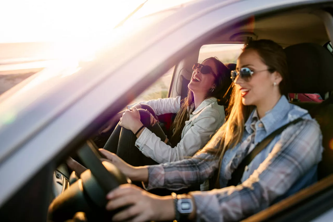 Dos chicas sonriendo dentro de un coche de Renting