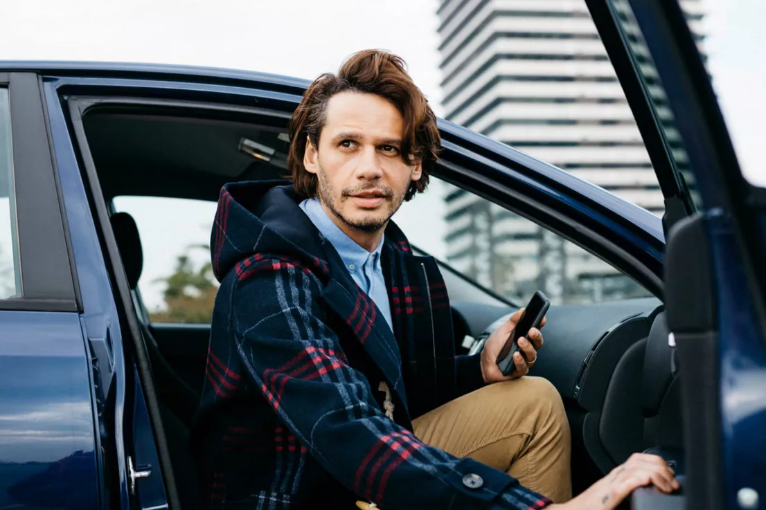 Un hombre sentado en un coche financiado con la puerta abierta