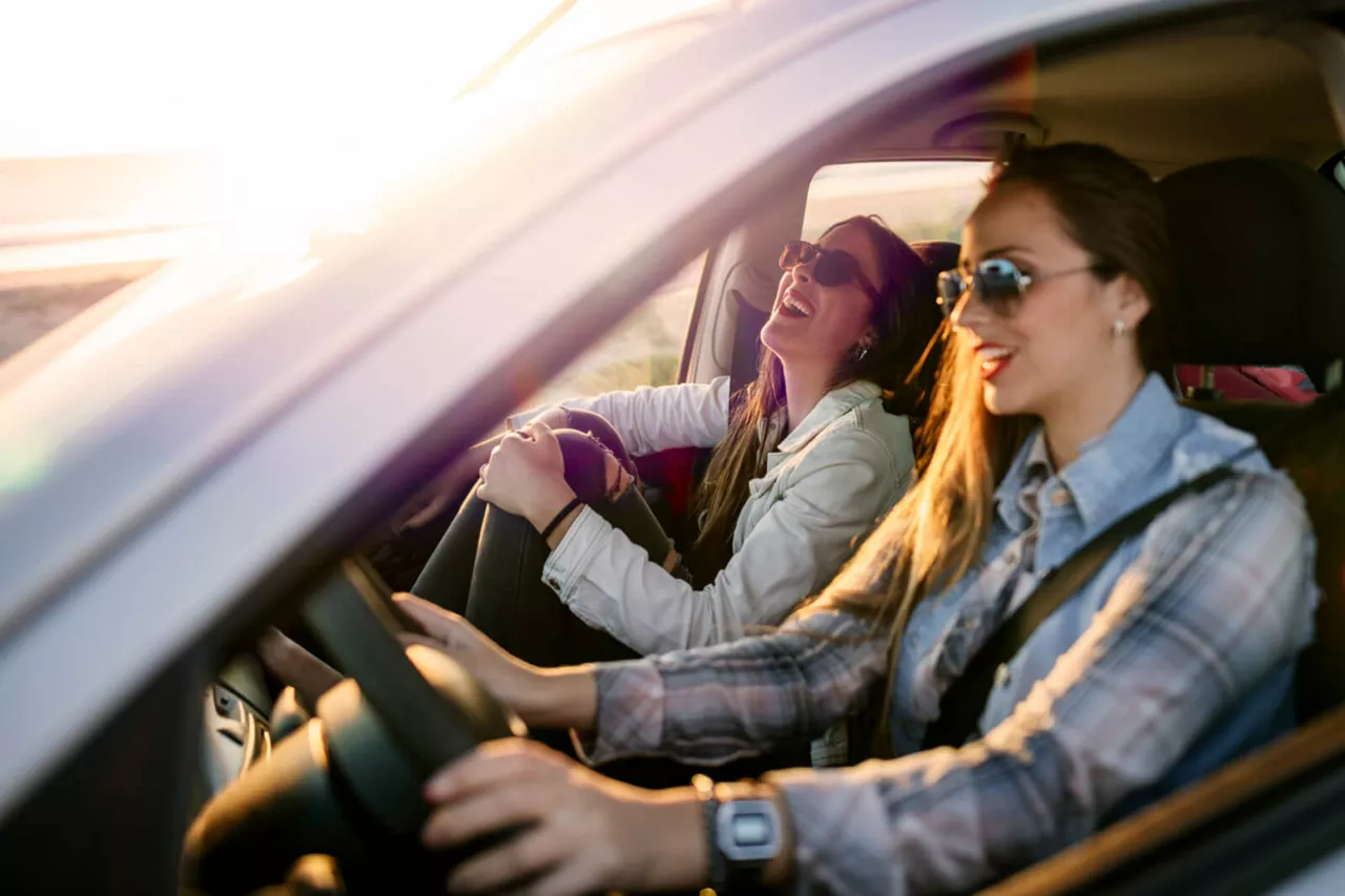 Dos chicas sonriendo dentro de un coche de Renting del Grupo Volkswagen