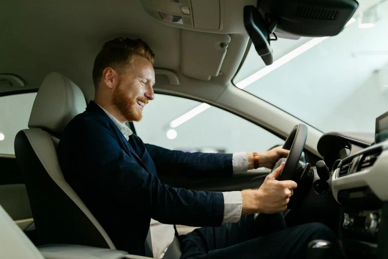 Un hombre al volante de un coche visto de costado