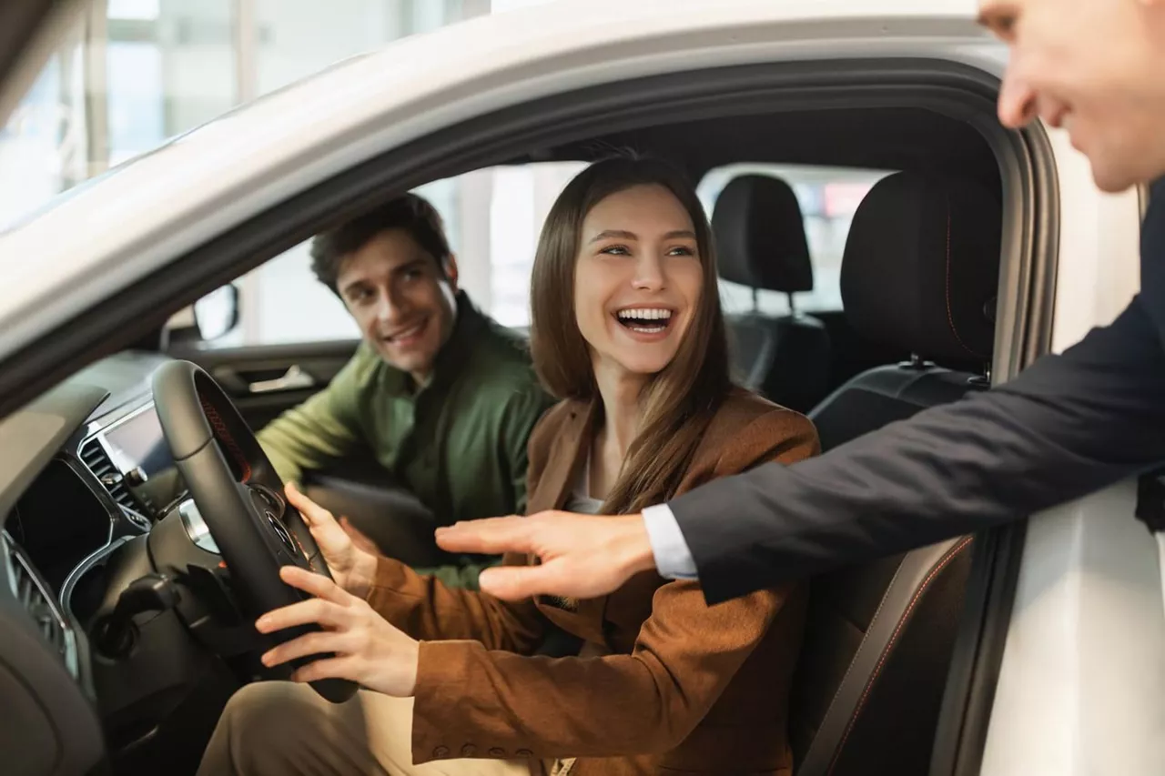 Una pareja sentada en un coche del Grupo Volkswagen hablando con un concesionario