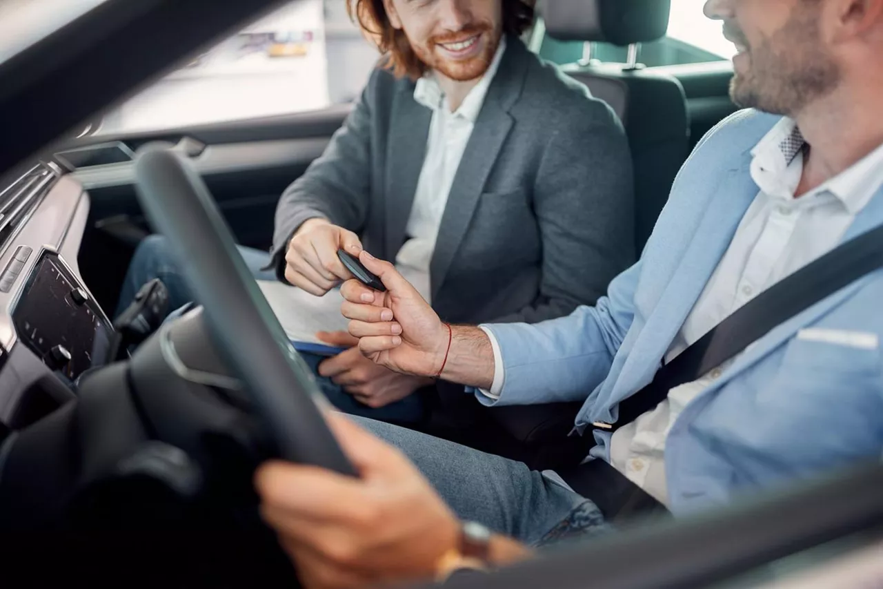 Dos hombres conversan en el asiento delantero de un coche