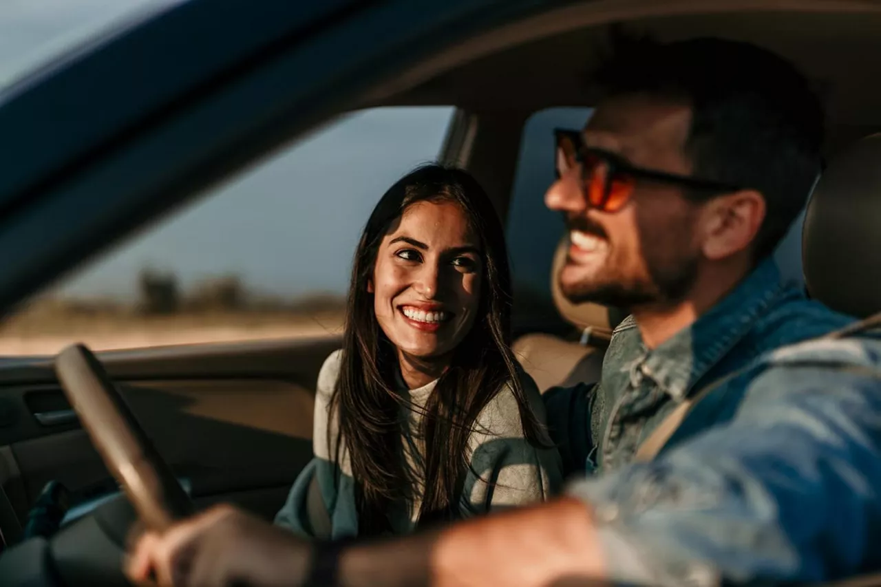 Una pareja conversa en el asiento delantero de un coche con cobertura seguro de coche en el extranjero