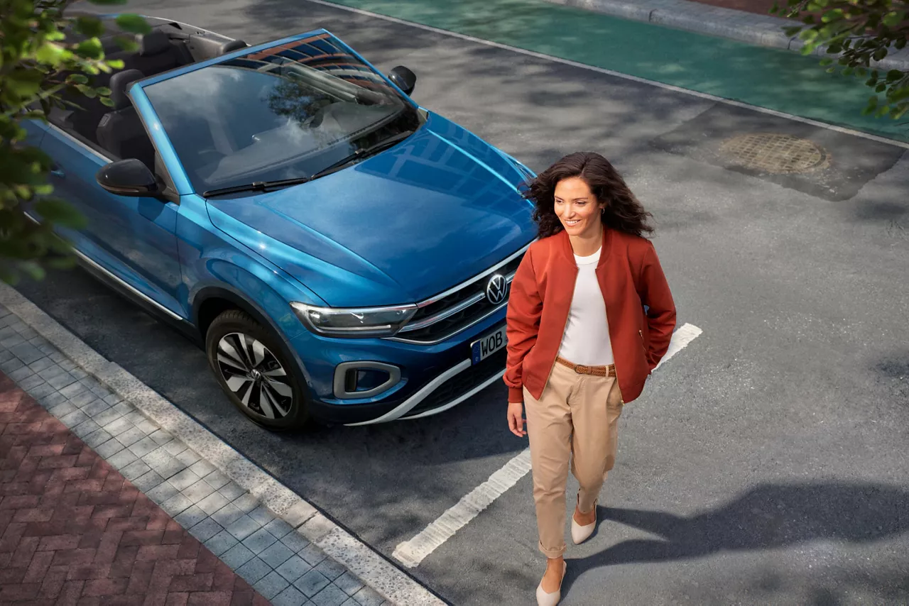 Una mujer caminando delante de un coche del Grupo Volkswagen aparcado en la calle, Leasing para empresas