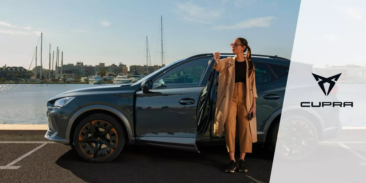 Una chica frente a un CUPRA de Rent-a-Car aparacado frente al mar. Alquiler CUPRA.