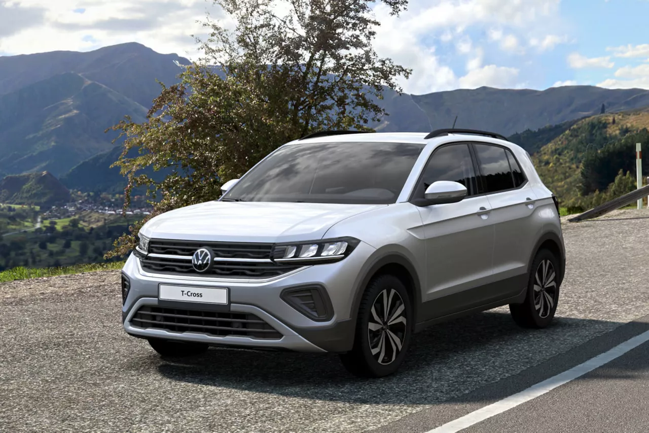 Vista frontal de un coche de Renting Volkswagen T-Cross, plata metalizado, de gasolina, etiqueta C, aparcado al lado de una carretera en la montaña.