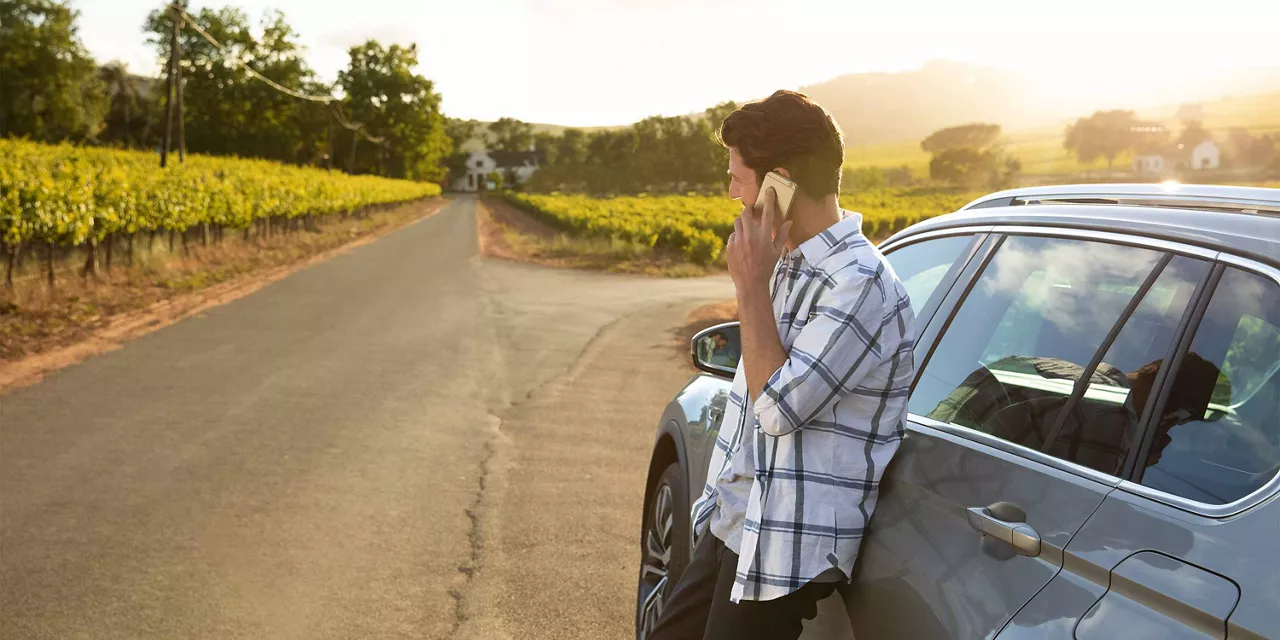 mann-lehnt-sich-gegen-auto-und-telefoniert-inmitten-der-natur