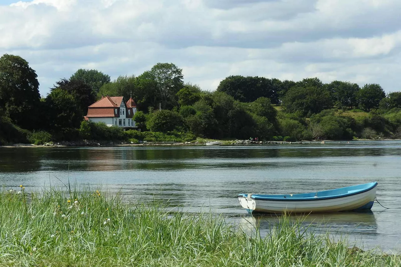 kleines-boot-auf-gewässer-mit-haus-im-hintergrund