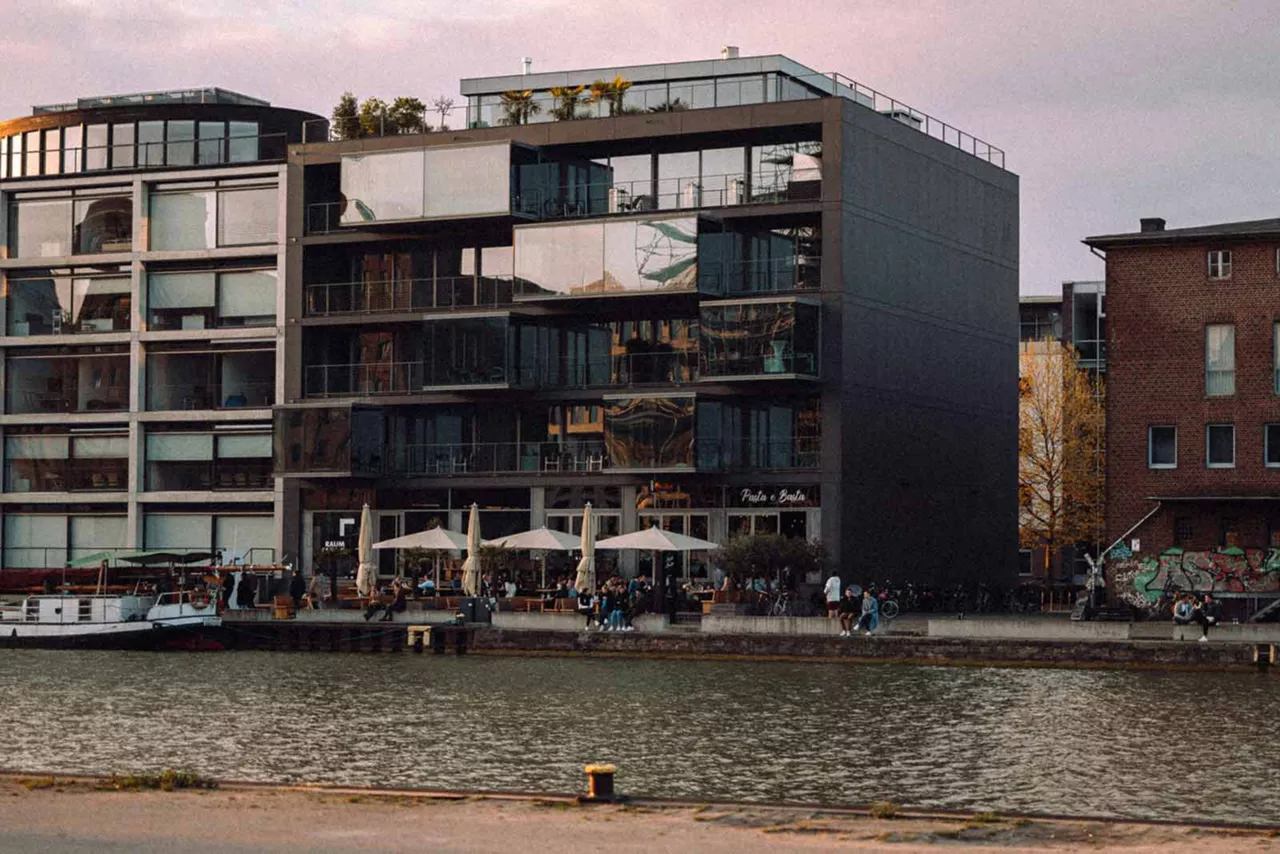 Moderne Gebäude an einer Hafenpromenade mit Außengastronomie am Wasser in Münster