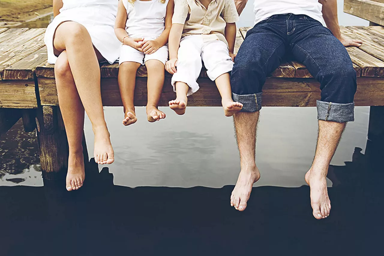 füsse-von-einer-auf-einem-steg-sitzenden-familie