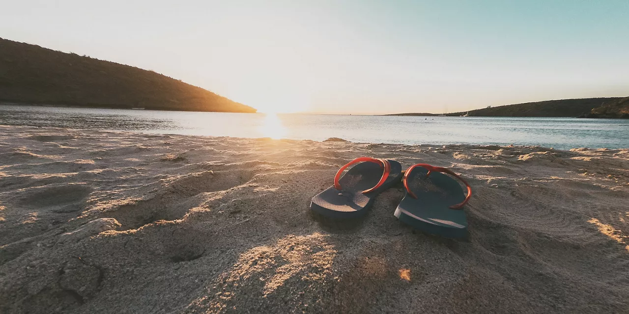 flip-flops-im-sand-am-meer-bei-sonnenuntergang